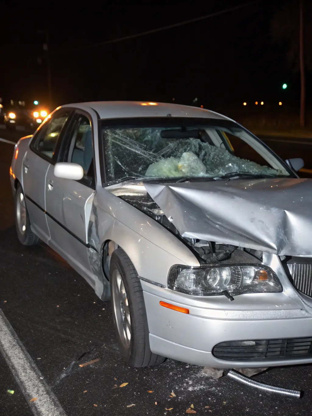 A slightly blurred image of a damaged car after an accident, focusing on the crumpled fender and broken headlight, symbolizing car accident cases handled by Texas Auto Protection.